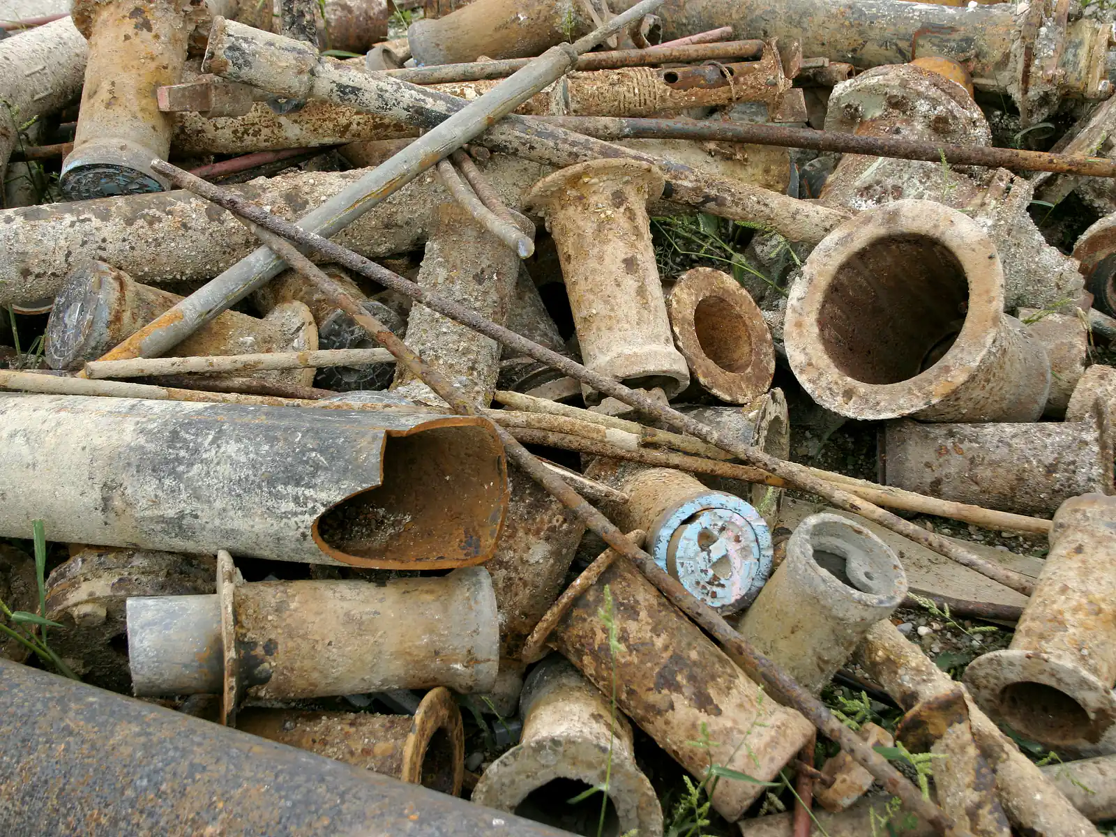 Tas de tuyaux et de raccords en fonte de démolition, parois épaisses et surface grise encroûtée