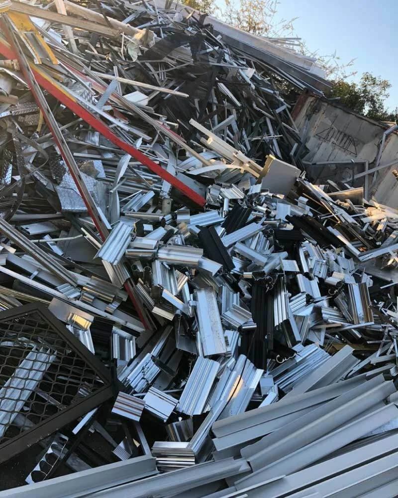 Tas de profilés d’aluminium extrudés, bruts, anodisés et thermolaqués, mélangés à des tôles et des grilles